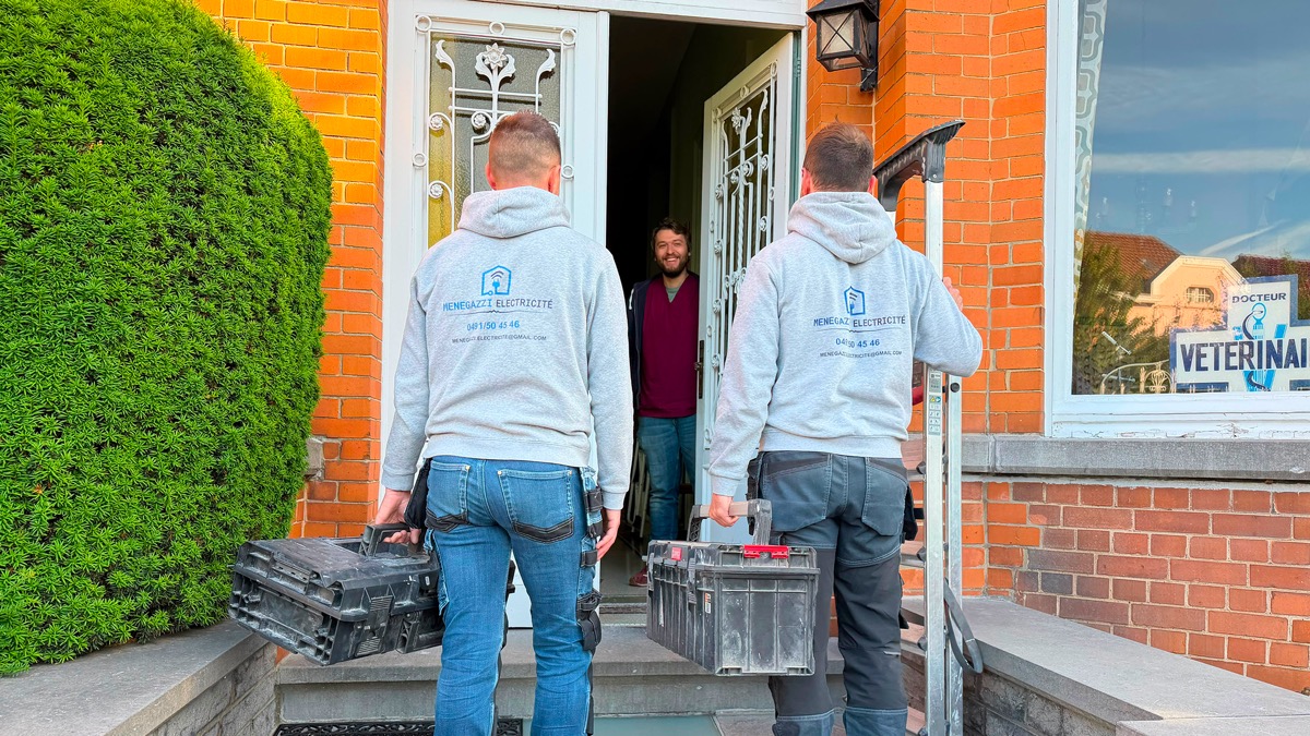 Menegazzi Electricité arrivant chez un client, caisses à outils à la main.