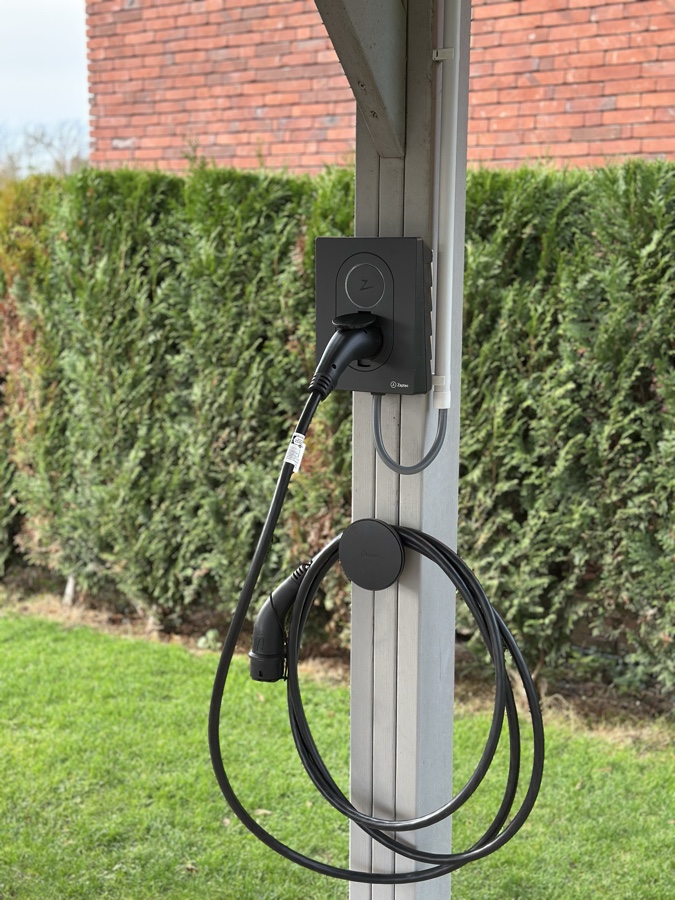 Borne de recharge intelligente installée sur poteau extérieur, devant une habitation.