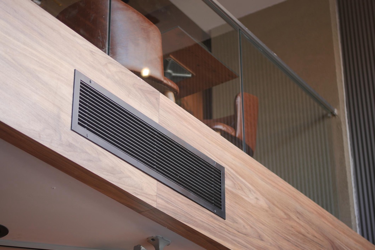 Grille de ventilation design intégrée dans une finition bois.