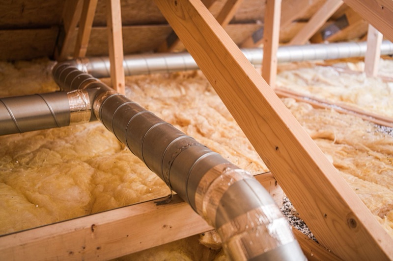 Réseau de gaines de ventilation tirées dans des combles isolés.